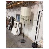 A FLOOR LAMP WITH A HANDWOVEN TASSEL LAMPSHADE