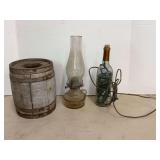 Rustic Decor Grouping Featuring Wooden Barrel, Glass Oil Lamp, and Illuminated Wine Bottle