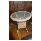 beige wicker side table with an inset glass top