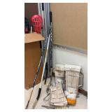 Lot of hockey sticks and goalie padding