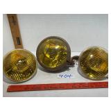Three amber colored vintage car lights