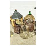 5 various size demi Johns in wicker baskets