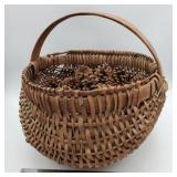 Folk art woven buttock basket w/ pine cones