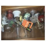 Several oil lamps, candles glassware in a cabinet