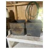 Two cast-iron planters with drainage holes in