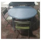 Blue round card table with 4 green folding chairs