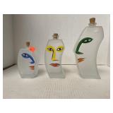 Three frosted glass bottles with faces painted on