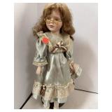 Porcelain doll on stand. 16in tall.