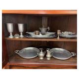 Contents of bottom of corner cabinet….hammered aluminum trays, pewter creamer/sugar, pewter serving trays and more….clear apple shaped tray on top shelf is plastic