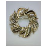 Vintage circle brooch designed by Star. 
Features a wreath-style arrangement of stylized, textured gold-tone leaves.