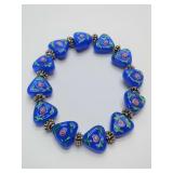 Blue opaque beaded stretchy bracelet featuring triangle-shaped beads with pink flowers, green leaves on both sides and silver-toned spacers.