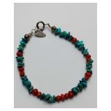 Southwestern-style bracelet featuring natural turquoise nuggets and red coral beads, traditionally handcrafted with sterling silver components.