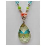Lenore Solmo handcrafted pendant necklace featuring a colorful, multi-bead chain and a large, teardrop-shaped crystal charm with a butterfly applique on the back.