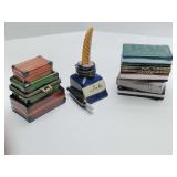 Porcelain trinket boxes a stack of books,  calligraphy inkwell and stack of suitcases. All are empty.