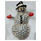 Retired 2003 Swarovski Snowman Brooch Signed with the Swarovski Swan logo, Features jet-black crystal buttons, red enameled mittens, and a black enameled top hat with a silver or gold-tone band.