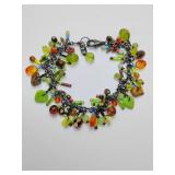 Dangle cluster charm bracelet featuring various green and brown glass beads and molded leaf charms on a dark metal chain.