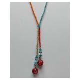 handmade beaded necklace featuring multicolored seed beads, clear accent beads, and two large red beads with black markings at the ends.