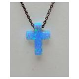 Tiny Blue Opal cross necklace, vibrant, shimmering cross-shaped pendant.  Lab-created or synthetic blue opal, known for its "play-of-color" effect that shifts in light. On a 925 Turkish silver adjusta