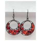 Dangle earrings in gunmetal-toned circular frame filled with a variety of faceted and smooth red beads and rhinestones of different shapes and sizes, creating a bold, mosaic-like effect.