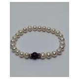 White freshwater pearl bracelet featuring a central purple amethyst gemstone bead, accented by two crystal-studded rondelle spacers.