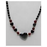 Beaded necklace with hematite or black onyx for the large central heart and small black beads, accented by warm carnelian or red jasper beads.