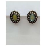 Vintage-style earrings feature oval cabochon stones surrounded by small crystals.