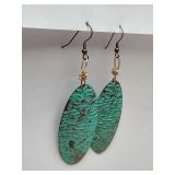 Drop earrings featuring an oval design with a green patina texture on a brass-colored base.