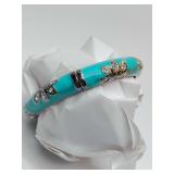 Hinged bangle bracelet featuring teal or aqua enamel, silver-tone metal, and floral designs embellished with clear stones.