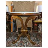 Victorian oval walnut parlor table featuring a marble top and ornate carved scroll legs.
