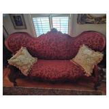 Vintage Victorian style parlor sofa with ornately carved mahogany wood and red floral damask upholstery