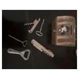 A metal treasure chest piggy bank with several vintage metal openers some with advertising