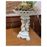 Porcelain cherub compote 12 inches wide 16 inches tall with a ornamental bird nest decor piece sitting in bowl