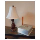 Bunny rabbit table lamp, textured, dark bronze resin flared cream-colored fabric shade 21"T. And, a storage box designed to look like an antique book, with  floral graphics 4"T x 13.5"L x 9.25"W.