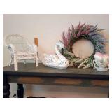 Charming collection of vintage and cottage-style decor, white wicker miniature doll chair, a crackle-finish resin swan figure, a floral lavender wreath, and a Hull Art Pottery double-handled vase.