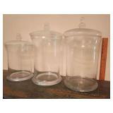 3 large glass apothecary jars approx 13" to 16"T. The jar on the right has a slightly different knob on lid than others.