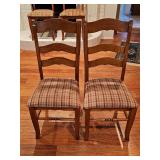 Two wooden ladder-back dining side chair features a medium brown warm stain and a padded seat upholstered in a rustic red, yellow, and green plaid fabric. 18.5 x 16.75 x 40 in tall. Seat height is 19 