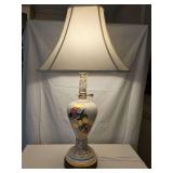 Hand-painted ceramic and porcelain table lamp featuring an ivory glazed body, vibrant floral rose motifs, and 22-karat gold or gilt trim accents sitting on an ornate brass-finished metal base. 33 in t