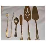 Gold color stainless serving pieces. Cake server, pie server, butter knife, condiment spoon, and tongs.