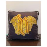 Versace 17” decorative throw pillow featuring a black or dark brown cover with a prominent gold Gothic-style monogram and Greek key border