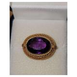 14 karat yellow gold brooch with purple stone.