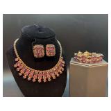 Vintage-style matching gold-tone necklace, bracelet and matching clip-on earring set featuring vibrant amethyst colored baguette and round rhinestones