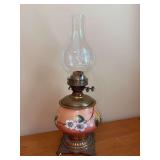 Antique glass oil lamp featuring a peach-toned gradient body decorated with hand-painted white floral blossoms and etched globe - 19” tall