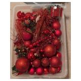 Clear storage container of red Christmas ornaments and decor