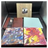 Photo albums in hand, painted canvases