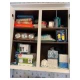 Contents of upper kitchen cupboards includes cookbooks, weather station, light bulbs, kleenex, plastic leftover containers, carafes, everyday glasses and mugs, measuring cups and everyday dinnerware