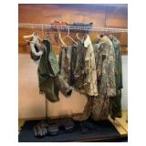 Variety of camo hunting clothes includes large rain poncho, 2XL coveralls, camo pants, jacket, desert camo upland shooting vest, hand warmer, men