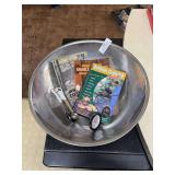 Large stainless steel mixing bowl with three cookbooks, measuring spoons and meat thermometer