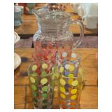 Clear glass pitcher with polka dots and four drinking glasses