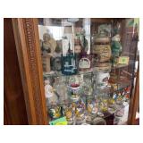 Top three shelves of cabinet include steins, Avon president figurines, decorative glass, Smurf glasses, etc
