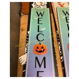 A welcome sign and two skeleton signs